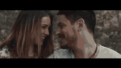 a man and a woman are looking into each others eyes .