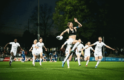 a group of female soccer players on a field with one wearing a black adidas top