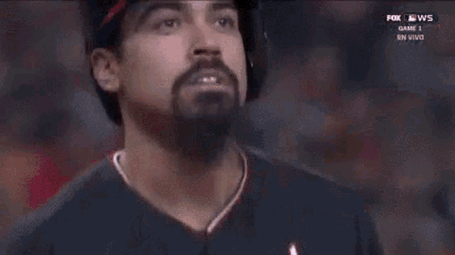 a baseball player with a beard is wearing a helmet and a red cap .