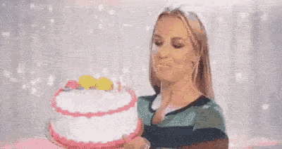 a woman is blowing out candles on a cake .