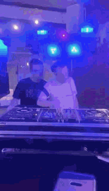 two men are playing music in a dark room with blue lights