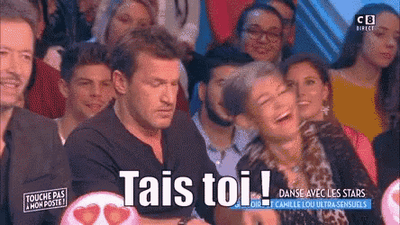 a man and a woman are laughing in front of a crowd and the woman is laughing with the words tai 's toi