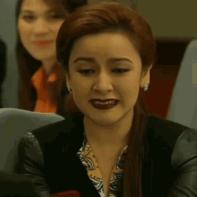 a woman with red hair is making a funny face while sitting in a chair .