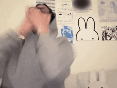 a man stands in front of a wall with a drawing of a bunny on it and a poster that says andy