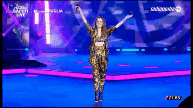 a woman stands on a stage with her arms outstretched in front of a screen that says radionorba tv
