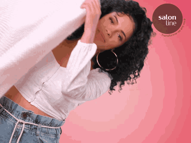a woman with curly hair is standing in front of a pink background with a salon line logo