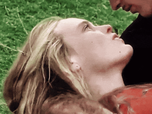 a close up of a woman 's face with a man behind her