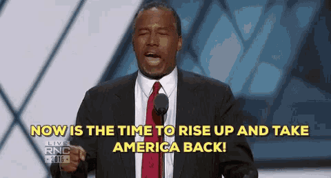 a man in a suit and tie stands in front of a microphone with the words now is the time to rise up and take america back