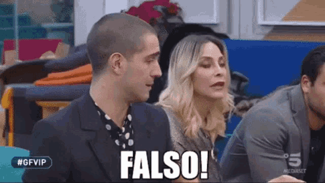 a man and a woman are sitting next to each other in a room and the man is saying falso .