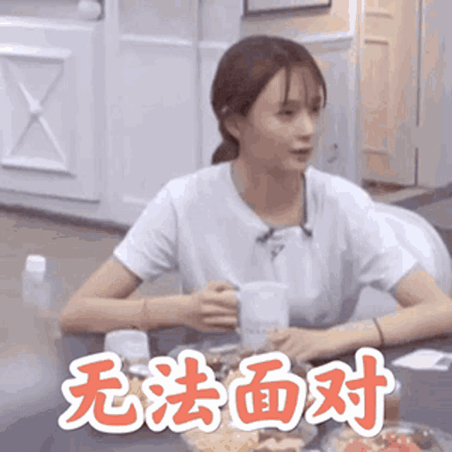 a woman is sitting at a table with a plate of food and a mug of coffee .