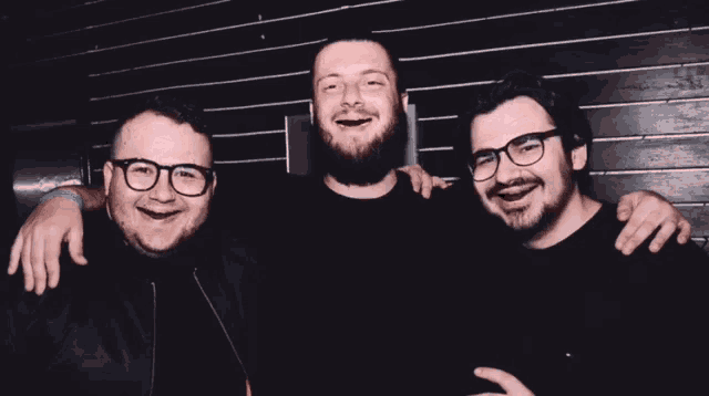 three men are posing for a picture and one of them has glasses on