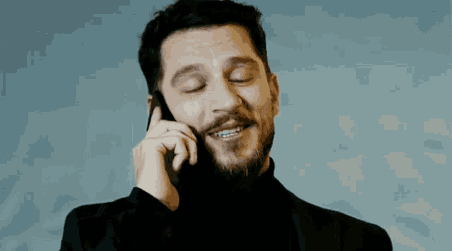 a man is smiling while talking on a cell phone