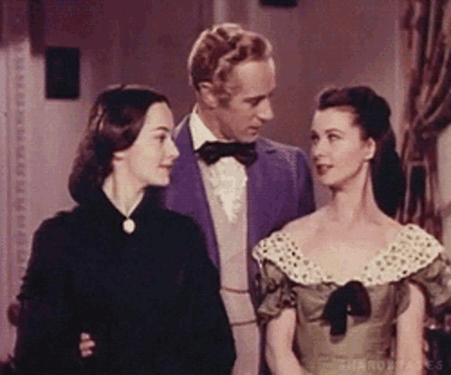a man and two women are standing next to each other and the man is wearing a purple jacket