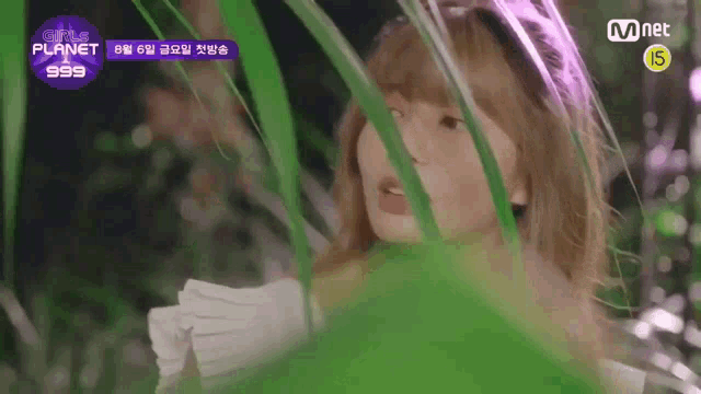 a girl is standing in a field of green plants and looking through the leaves .