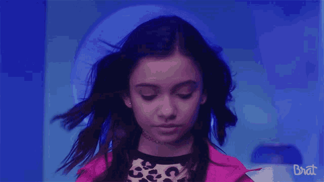 a girl in a leopard print top and a pink jacket with brat written on the bottom