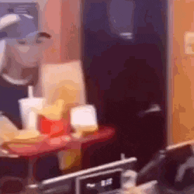 a blurry picture of a person standing in front of a mcdonald 's counter with french fries .