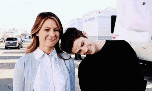 a man and a woman are posing for a picture in a parking lot