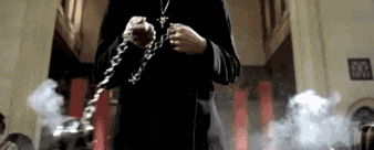 a man in a black robe is holding a chain around his neck .