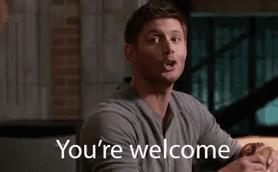 a man is sitting at a table with a sandwich in his hand and a sign that says `` you 're welcome '' .