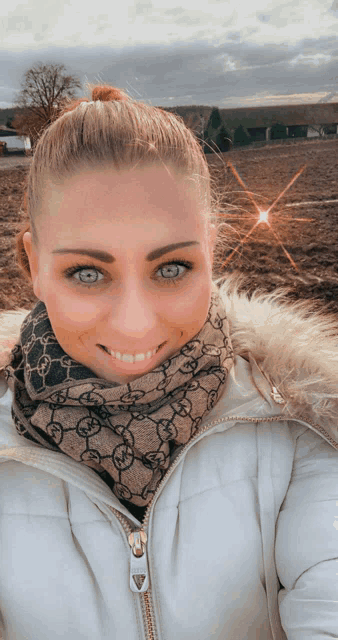 a woman wearing a gucci scarf and a white jacket is smiling