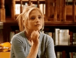 a woman in a blue sweater is sitting in front of a bookshelf .