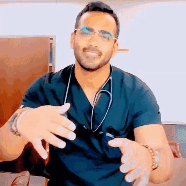 a man wearing a scrub top with a stethoscope around his neck is talking