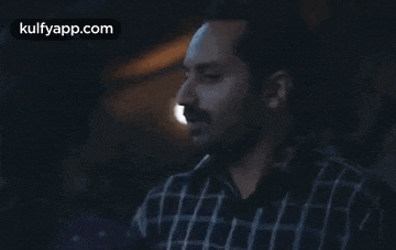 a man in a plaid shirt is standing in the dark .