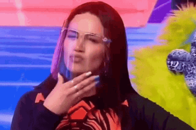 a woman is wearing a face shield and making a funny face .