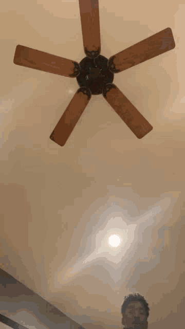 a person is standing in front of a ceiling fan in a room .