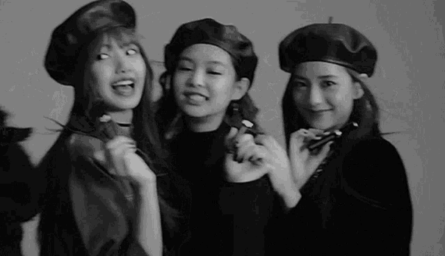 a group of three women wearing beret hats are posing for a black and white photo .