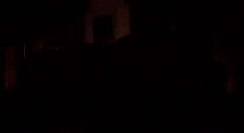 a man sits on a couch in a dark room with a picture on the wall