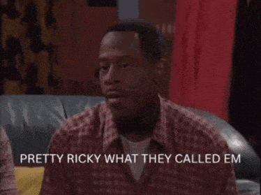 a man in a plaid shirt is sitting on a couch and says  pretty ricky what they called em 