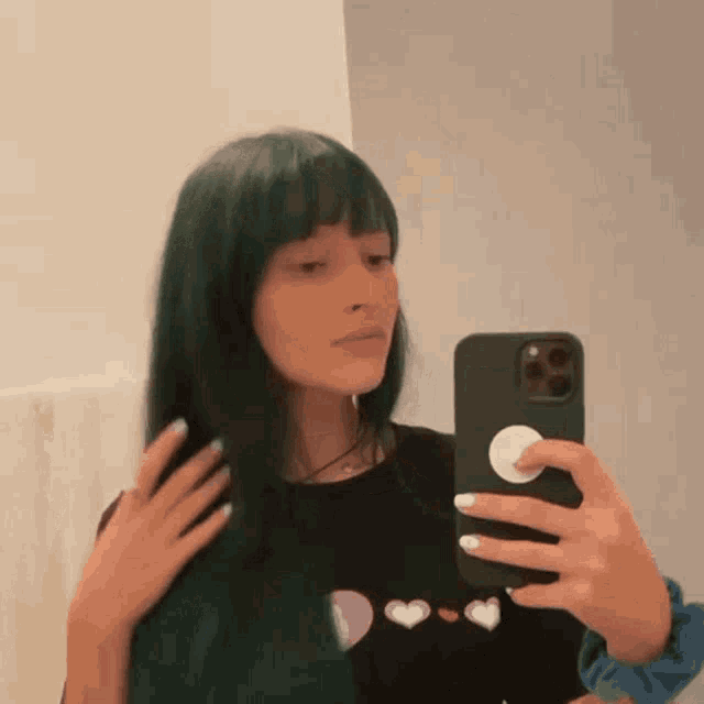 a woman with green hair is taking a picture of herself in the mirror .