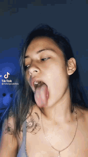 a woman with a tattoo on her shoulder is sticking her tongue out .