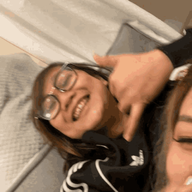 a woman wearing glasses is smiling while laying on a bed