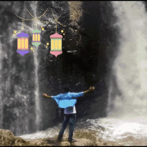a man stands in front of a waterfall with his arms outstretched and lanterns around him