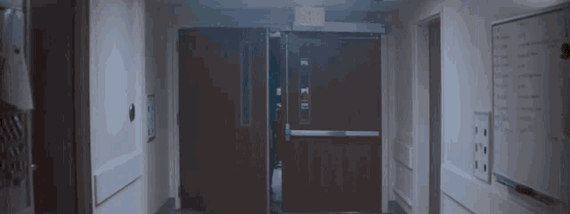 a man is walking through a hallway with an exit sign