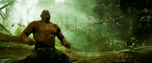 a man without a shirt is standing in the middle of a forest ..