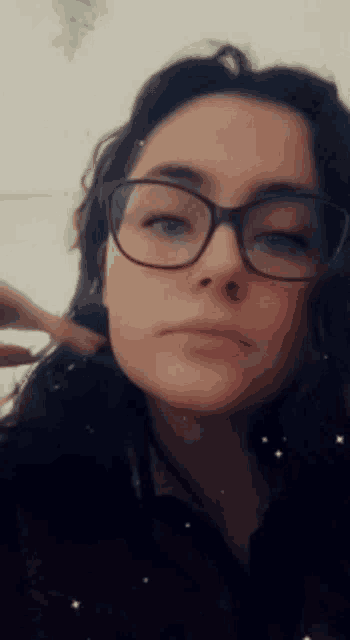 a woman wearing glasses and a black shirt looks at the camera .