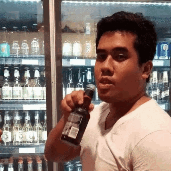 a man in a white shirt is holding a bottle of alcohol