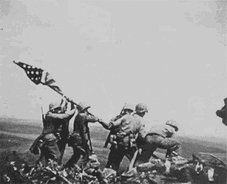 a black and white photo of soldiers raising an american flag
