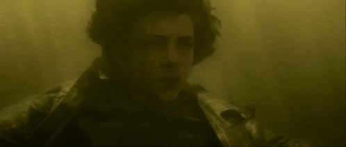 a man with curly hair is swimming in the water in a foggy room .