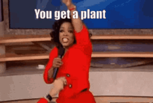 a woman in a red dress is holding a microphone and says " you get a plant "