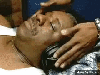 a man is laying down with his eyes closed and his head is being massaged by someone .