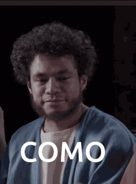 a man with curly hair and a beard has the word como written on his shirt