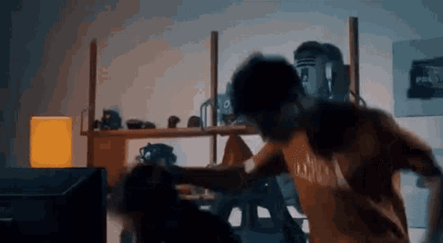 two men are fighting in a living room with a shelf full of toys .