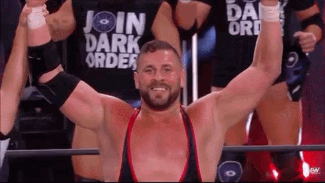 a man in a wrestling ring with his arms in the air and a shirt that says join dark order .