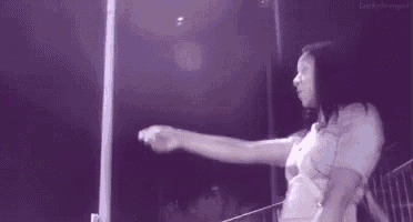 a woman in a white shirt is standing in front of a pole with her arms outstretched .