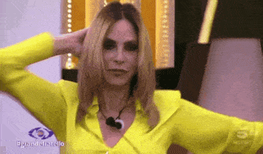 a woman in a yellow shirt is holding her hair in her hands