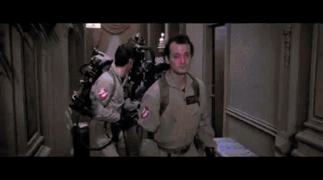 a group of people are running through a hallway with a red light coming out of a door .